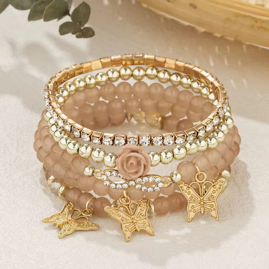 Stack of beaded bracelets with butterfly charms on a light background